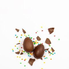 Easter chocolate eggs and colorful decorations on a light background. Easter concept, easter treats. Square. Flat lay, top view