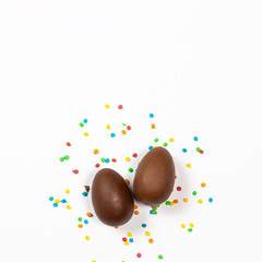 Easter chocolate eggs and colorful decorations on a light background. Easter concept, easter treats. Square. Flat lay, top view