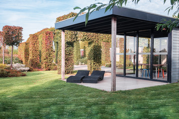 Two black loungers under an overhang to enjoy the sun in the beautiful autumn garden - 316834176