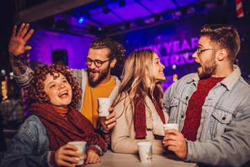 Friends drinking hot wine and having fun on outdoor concert. Celebrating new year