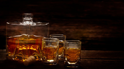 Whiskey bottle and whiskey glasses stand on a dark wooden table, tasting in the distillery