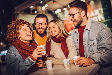 Friends drinking hot wine and having fun on outdoor concert. Celebrating new year