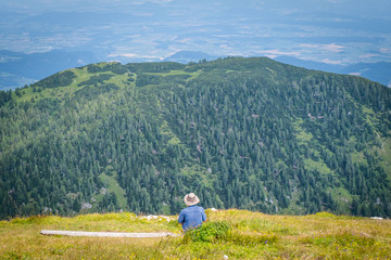 Naklejka na ściany i meble Summit of mountain Hochobir with man on bench, Carinthia, Austria