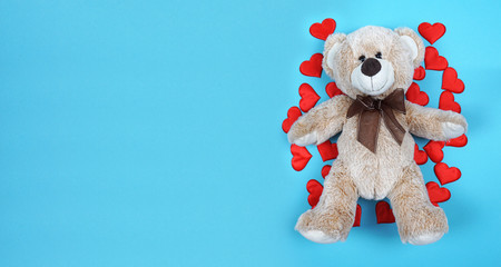 Teddy bear with red hearts on a blue background. Concept for Valentine's Day.