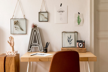 Design scandinavian interior of home office space with a lot of mock up photo frames, wooden desk, brown chair, neon letter, office and personal accessories.  Stylish neutral home staging. Template.