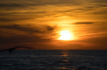 Fototapeta na wymiar Wellen und Meer mit romantischen Sonnenuntergang und brennenden atemberaubenden Himmel am Horizont 