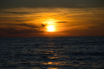 Wellen und Meer mit romantischen Sonnenuntergang und brennenden atemberaubenden Himmel am Horizont 