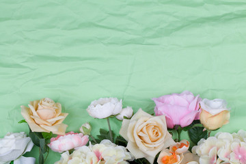 Various different flowers with vivid colours on rumpled green background.