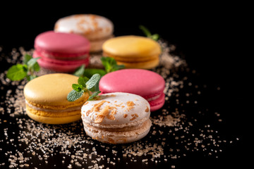Macarons or cake macaroon with mint on black background with copy space for text. Colorful French or Italian dessert. Sweet food
