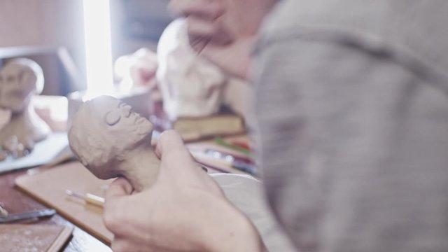 Young artist sculpting bust of woman with Plasticine (non-drying clay)