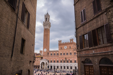 Fototapeta premium piazza del campo siena with peoples in downtown in tuscany in italy italian city with clouds sky in spring torre del mangia tower of palazzo di città historical palace architecture in central square