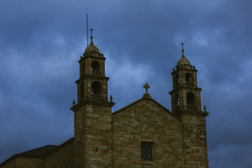 Fototapeta premium The Virxe da Barca sanctuary, a church located in Muxía, Spain.Church on the coast of Atlantic Ocean at the end of the Santiago path. Twilight, view of the church. Temple against a dramatic sky.