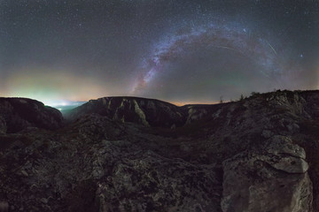 Fototapeta na wymiar 360 degrees Panorama. Above the rocky landscape of the great gorge is the Milky Way with orionids meteors and small airglow. The sky is illuminated by the city behind the hill.