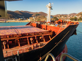 The bow of a ship with closed hold covers is photographed from a height in a seaport surrounded by...