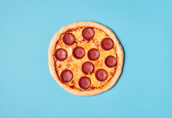 Pizza salami on a blue background. Whole pizza pepperoni. Food