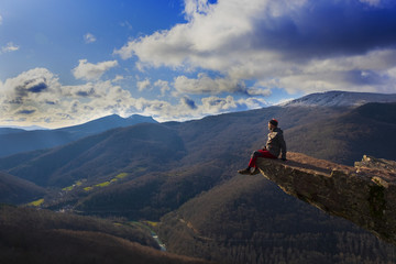 Fototapeta na wymiar Man appreciating the landscape sitting on a rock protruding from the mountain, Mirador de Zamariain in the Arce Valley, Navarra