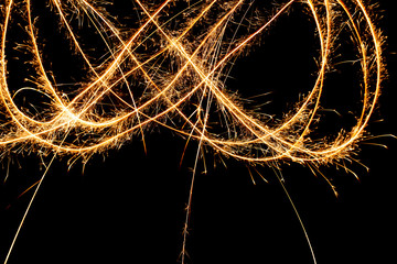 Abstract pattern of sparks and bright light beams of Golden color on a black background