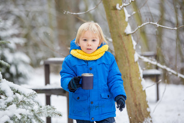 Sweet toddler boy, playing with snow on playground