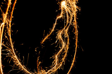 Abstract pattern of sparks and bright light beams of Golden color on a black background