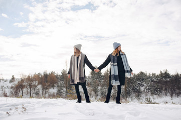 Fototapeta na wymiar Cute girls walking in a winter park. Sisters have fun with snow. Ladies in a cute hats