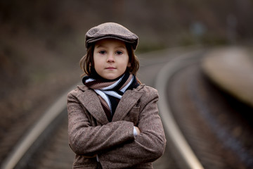 Adorable boy on a railway station, waiting for the train
