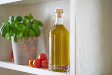closeup kitchen shelf olive oil bottle pot parsley in mediterranean style, green yellow red vegetarian vegetable in sunny summer feeling,copy space blurred
