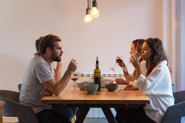Joyful friends talking while drinking red wine. Friends having pleasant conversation during dinner....