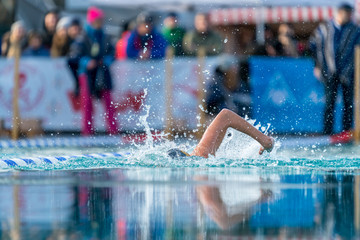 Woman swimming in an outdoor pool at an ice swim competition