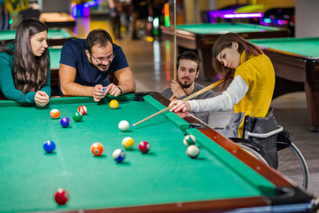 Disabled girl in a wheelchair playing billiards