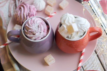 Two cups of coffee with meringues and marshmallows, Turkish delight on a plate, hearts, illumination, against the background of a window, homeliness, Valentine's day