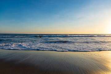 Ocean waves on the beach with beautiful sunset at one of the famous beaches of Canggu, Bali, Indonesia.