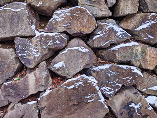 view of a rock wall, dusted with snow after a winter storm
