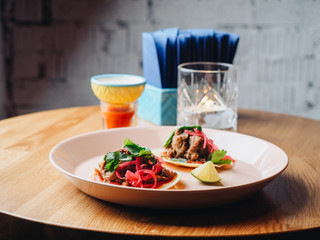 Tacos with meat, onion, greens, lime. plate on the table
