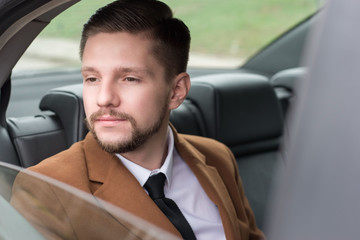 portrait of a young guy with a beard. Businessman in a car in the passenger seat rides to the office, to work