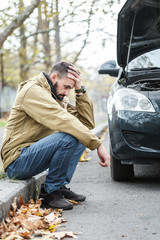 Guy is repairing car on the road