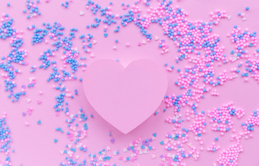 Paper pink heart on a background of decorative balls in blue and pink
