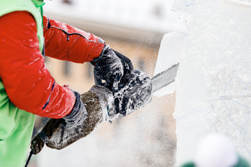 Ice sculpture carving man use chainsaw cut frozen winter