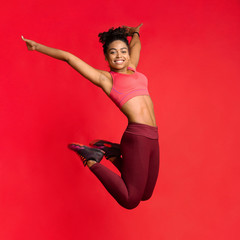 Carefree athletic girl in sportswear happily jumping up