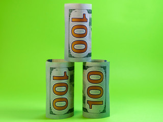 Three hundred dollar banknotes rolled up in a tube on a green background, money stands in a pyramid with copy space