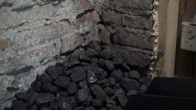  Man with shovel and heap coal in the basement. Coal heating for private house. preparation for winter season. 4K flat image