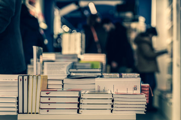 Pile of books, abstract blurred background in book store or in library. Unrecognizable people,...