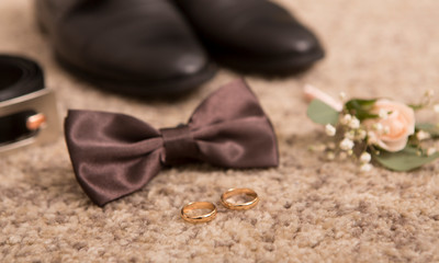 Close up of wedding bow tie, belt and groom shoes on floor