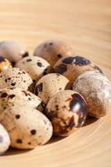 Quail eggs stacked on a yellow bamboo plate.
