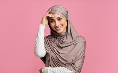 Shy muslim girl in hijab smiling and touching head in embarrassing