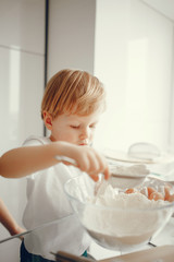 Obraz na płótnie Canvas Child in a kitchen. Little boy with a dough.