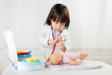 toddler girl pretend play  doctor role  at home against white background