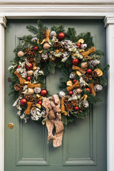 Nice Christmas wreath hanging on a traditional blue or green wooden door an exclusive mews with small houses in Chelsea, a wealthy borough of London. © ManuPadilla
