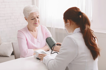 Doctor measuring blood pressure of senior female patient