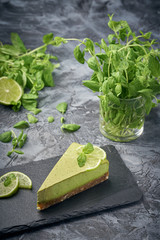 Slice of raw green cheesecake with lime and mint, decorated slice of lime. Healthy organic summer dessert pie.