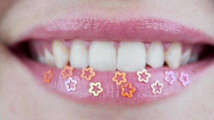Close view of bright female lips. Smile of a woman with decorative stars on her lower lip and perfect teeth 